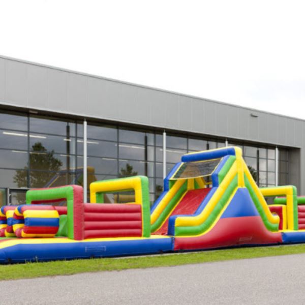 Opblaasbare stormbaan Colour Run van 21 meter met kleurrijke obstakels en glijbaan – perfect voor sportdagen en evenementen.